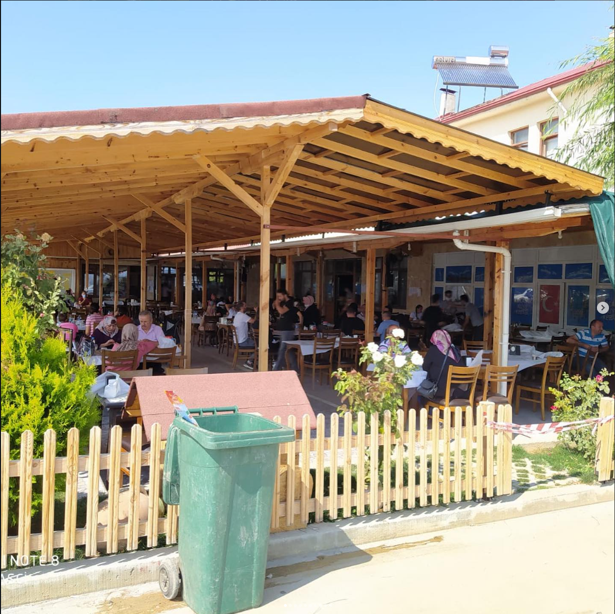 Ahşap çatılı verandanın dışarıdan görünümü ve oturan misafirler